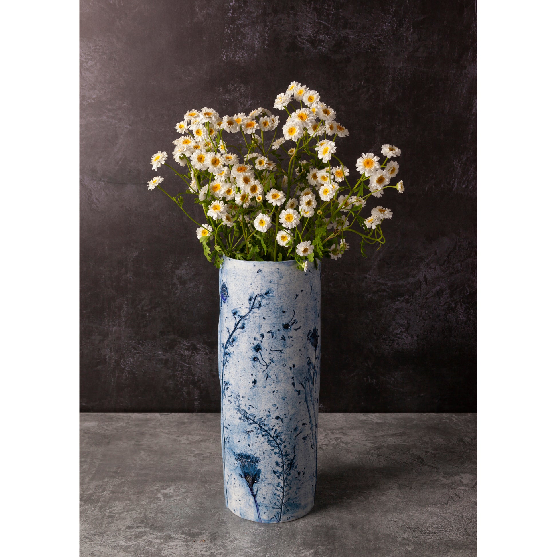 Blue and white vase with flowers against a dark background