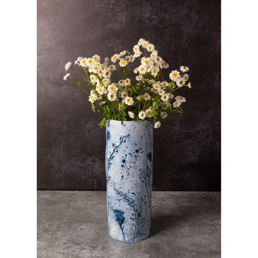 Blue and white marbled vase with flowers against a dark background