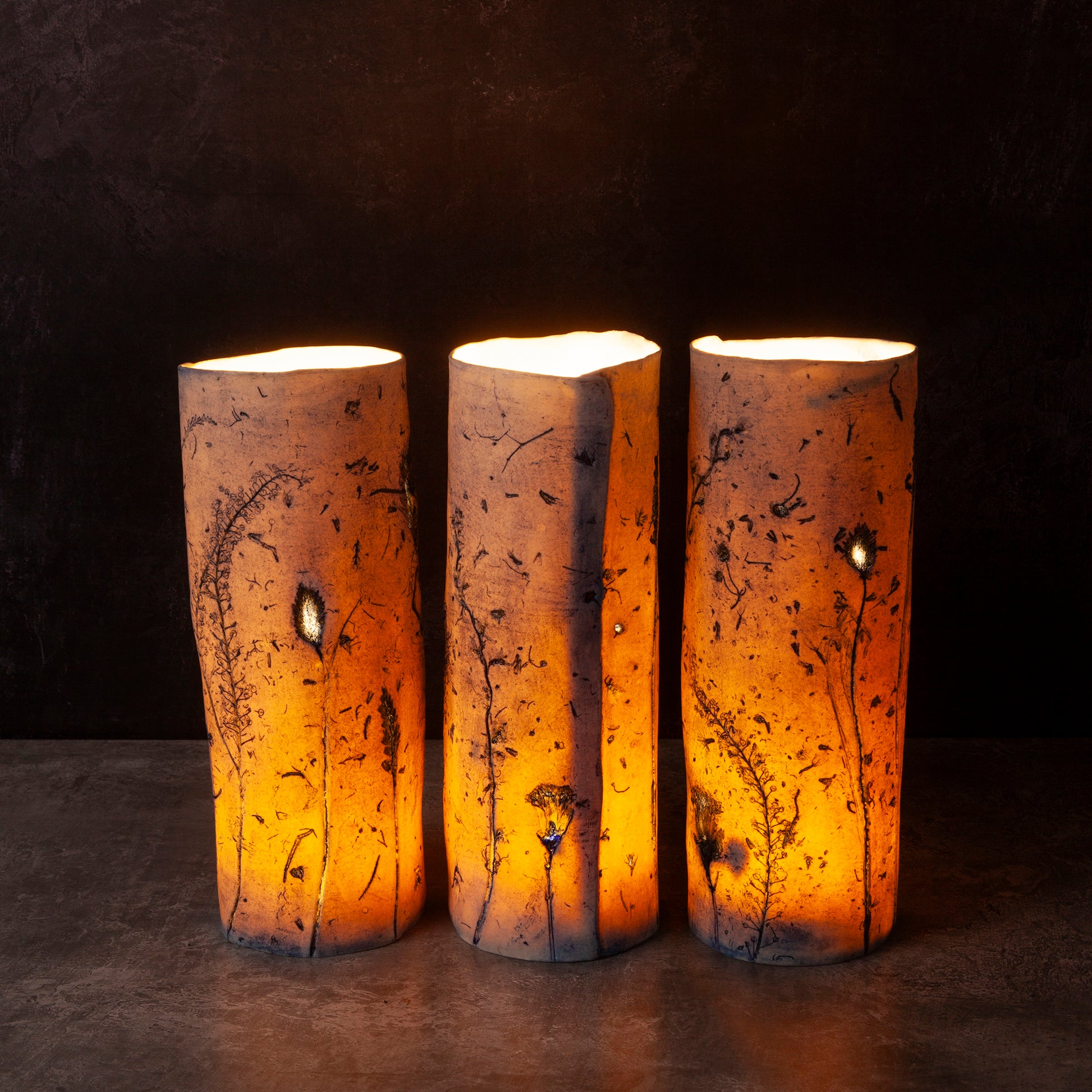Three porcelain candle holders with a warm glow on a dark background