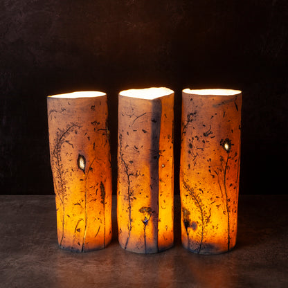 Three porcelain candle holders with a warm glow on a dark background