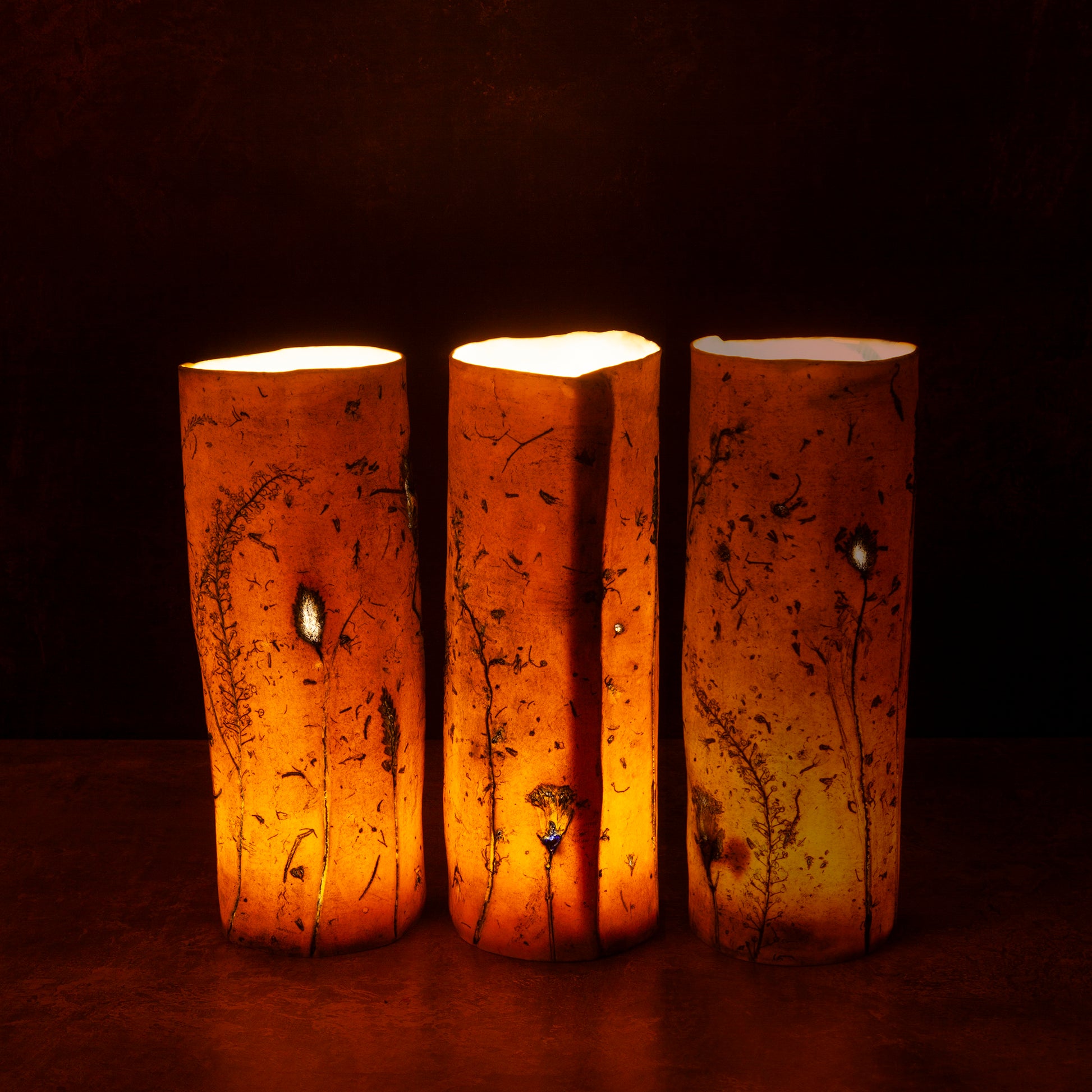Three porcelain lanterns with a warm glow on a dark background