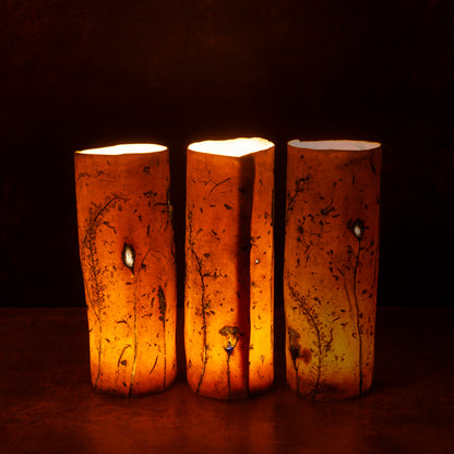 Three porcelain lanterns with a warm glow on a dark background