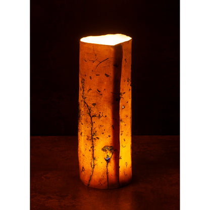 Porcelain Cylindrical night light vase with a warm glow on a dark background