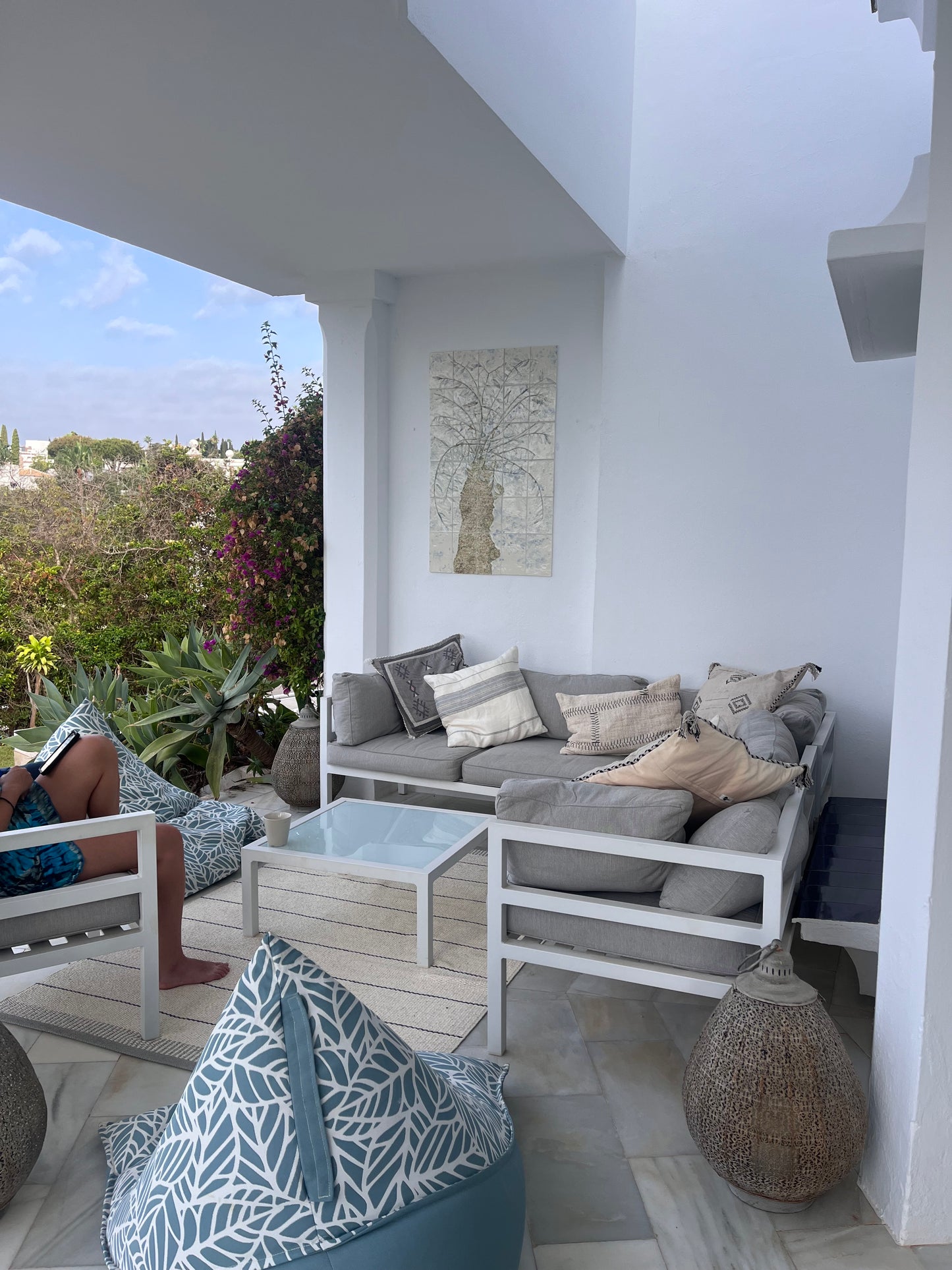 Outdoor mediteranean setting with furniture and decor. Including a porcelain tile panel on the wall, depicting an olive tree.