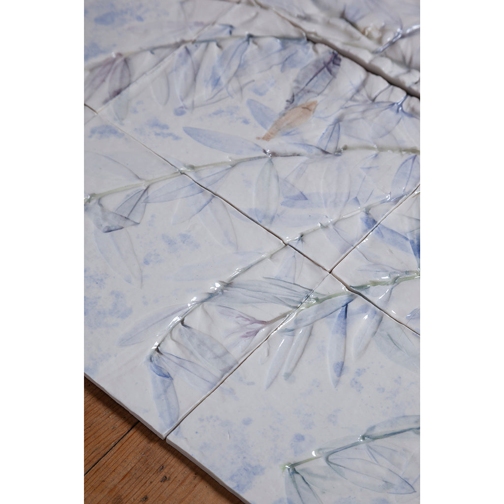 Detail of Large porcelain tile panel of an olive tree. Looking at leaves and branches. Blue and browny green colours on a white background